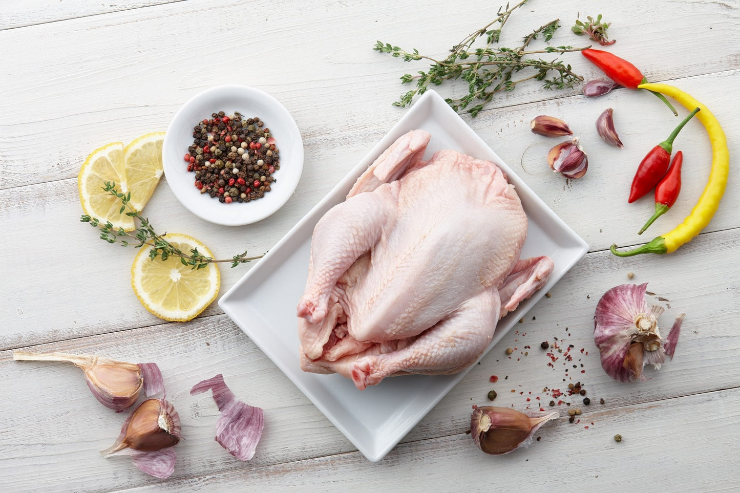 Raw chicken, herbs and spices on white wooden background