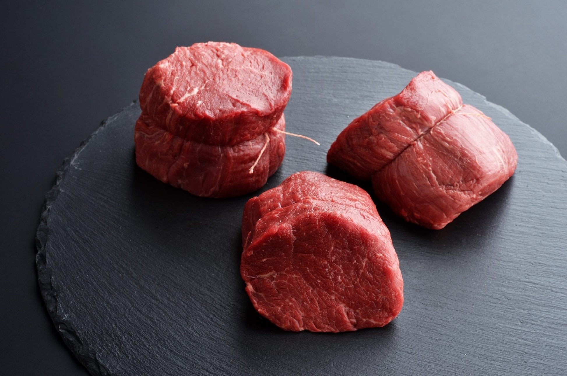 Three fresh raw Prime Black Angus beef steaks on stone background